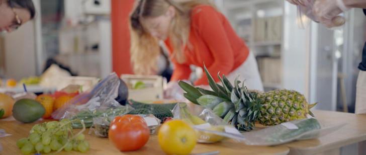 Au premier plan des fruits et légumes en provenance de plusieurs pays prêts à être emballés et étiquetés individuellement pour être analysés